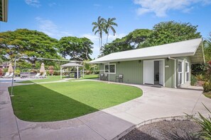 Un bâtiment à l’extérieur verdoyant, doté d’un patio couvert et d’une pelouse bien entretenue.