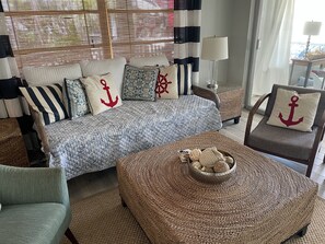 Ein gemütliches Wohnzimmer mit einem großen Bett, einem Sessel, einem gewebten Hocker und einer Lampe.