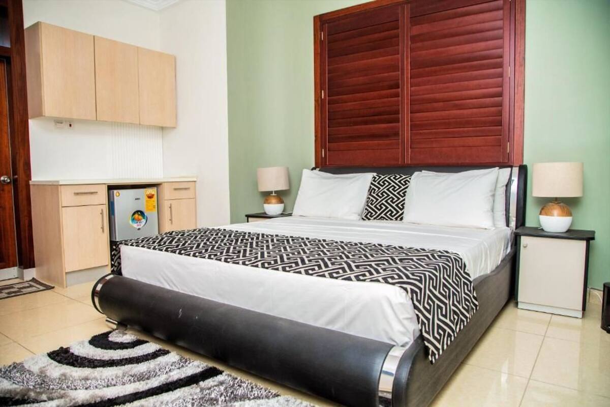 A bedroom with a bed, two bedside tables, a wardrobe, and a desk.