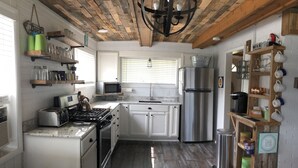 Una cocina con gabinetes blancos, un refrigerador de acero inoxidable, una estufa a gas y un techo de madera.
