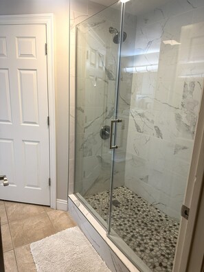 A glass-enclosed shower with a marble floor and a white door. - Gorgeous 2 Bedroom, King Beds; Spectacular Gulf Views; Newly renoated (Panama City Beach)