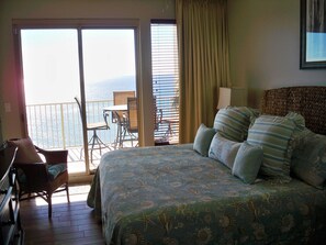 A bedroom with a bed, a chair, a table, and a view of the ocean through a sliding door. - Gorgeous 2 Bedroom, King Beds; Spectacular Gulf Views; Newly renoated (Panama City Beach)