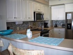 Una cocina con armarios blancos, un microondas, una estufa y un refrigerador.