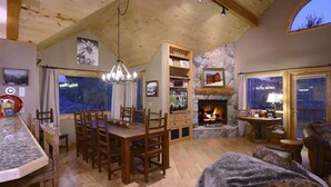 A cozy interior with a dining area, fireplace, and large windows. - Ruby Retreat (Crested Butte)