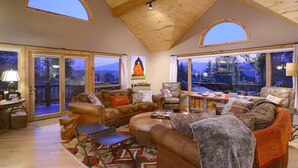 A spacious living room with a high ceiling, large windows, and a cozy fireplace. - Ruby Retreat (Crested Butte)