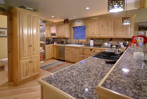 A kitchen with wooden cabinets, granite countertops, a stove, and a window.