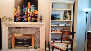 A room with a fireplace, a bookshelf, and a painting of a cityscape. - Better Bed House (Richmond)