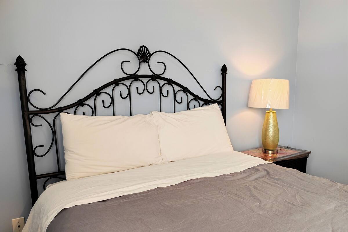 A bed with a metal headboard, a bedside lamp, and a power outlet.