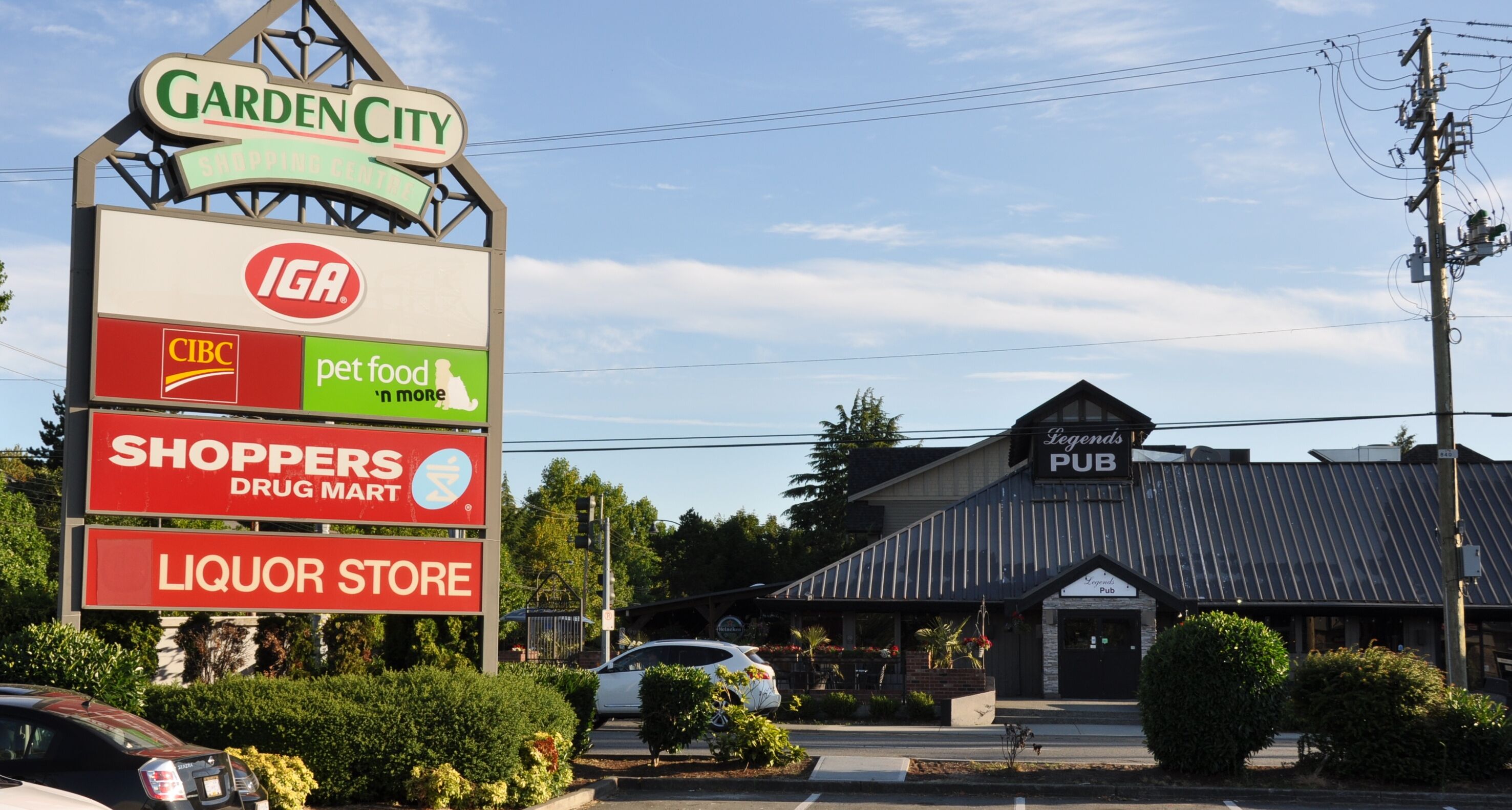 A sign for Garden City Shopping Centre with various store names including IGA, CIBC, pet food, shoppers drug mart, and liquor store.
