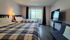 A hotel room with two beds, a TV, a sofa, a lamp, and a balcony with a view. - Better Bed House (Richmond)