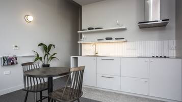 Una cocina moderna con armarios blancos, una campana extractora de acero inoxidable y una mesa redonda con dos sillas.