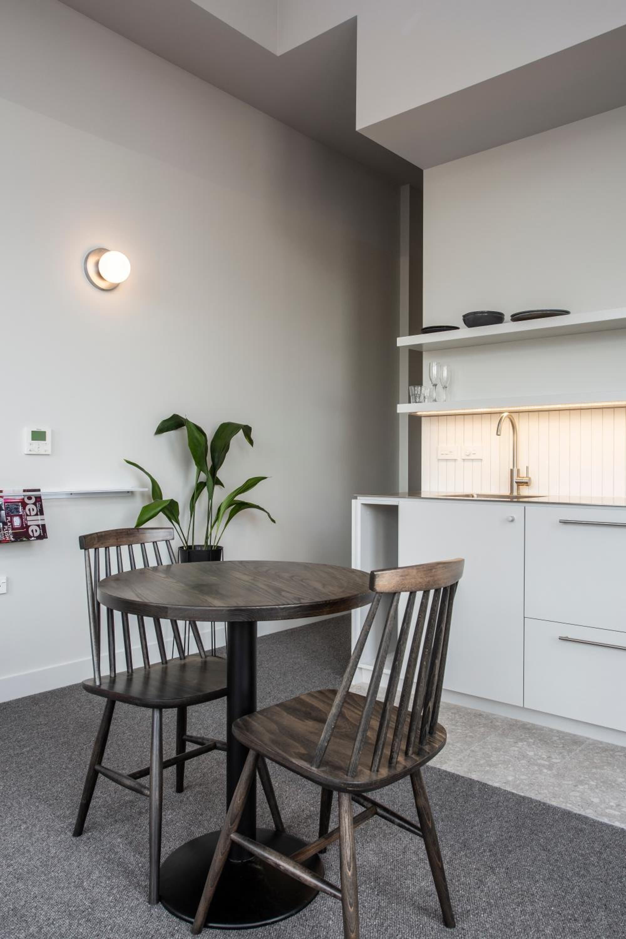 A modern kitchen with white cabinets, a built-in sink, and a round dining table with four wooden chairs.