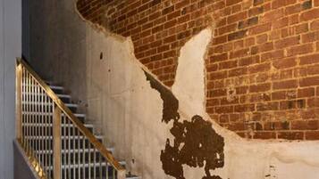 A staircase with a brick wall and peeling paint.