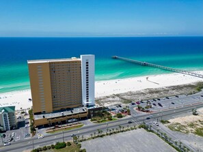 Ein Hochhaus-Hotel mit Parkplatz und Blick auf den Strand.