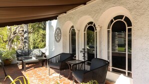 Une terrasse extérieure avec un canapé, deux fauteuils, une table et un mur décoratif.