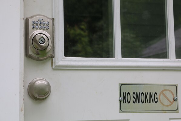 A door with a keypad lock and a 'No Smoking' sign.