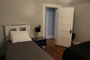 A bedroom with a bed, a bedside table with a lamp, a nightstand, and a door leading to another room. - Whole House, 5 minutes by car to OU, 2 Bedroom, 1.5 bath, Smart TV, FREE Wi-Fi (Athens)