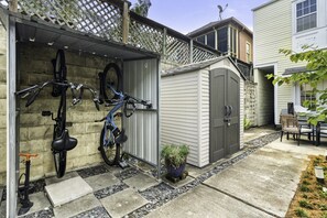 A garage with two bicycles mounted on the wall, a small shed, and a patio area with a table and chairs.
