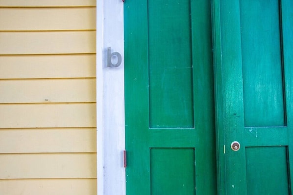 Une porte verte avec une lettre « b » blanche sur un mur jaune.