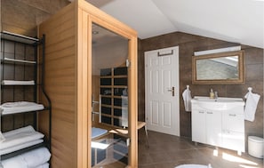 A modern bathroom with a wooden vanity, a glass shower enclosure, and a white sink. - Awesome Home in Lepajci w/ Sauna, Wifi and 3 Bedrooms (Krapina)