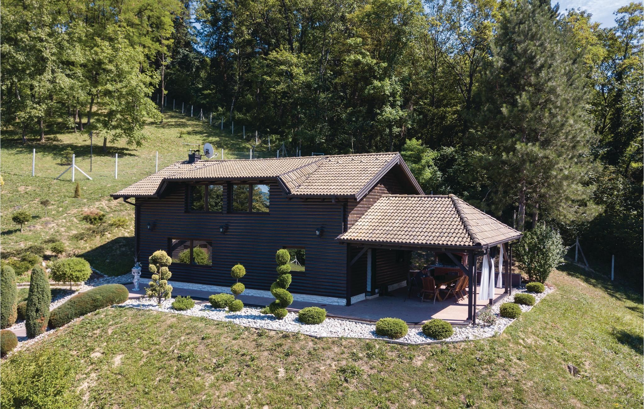 A two-story house with a tiled roof, surrounded by a well-maintained garden with trimmed bushes and a gravel pathway.
