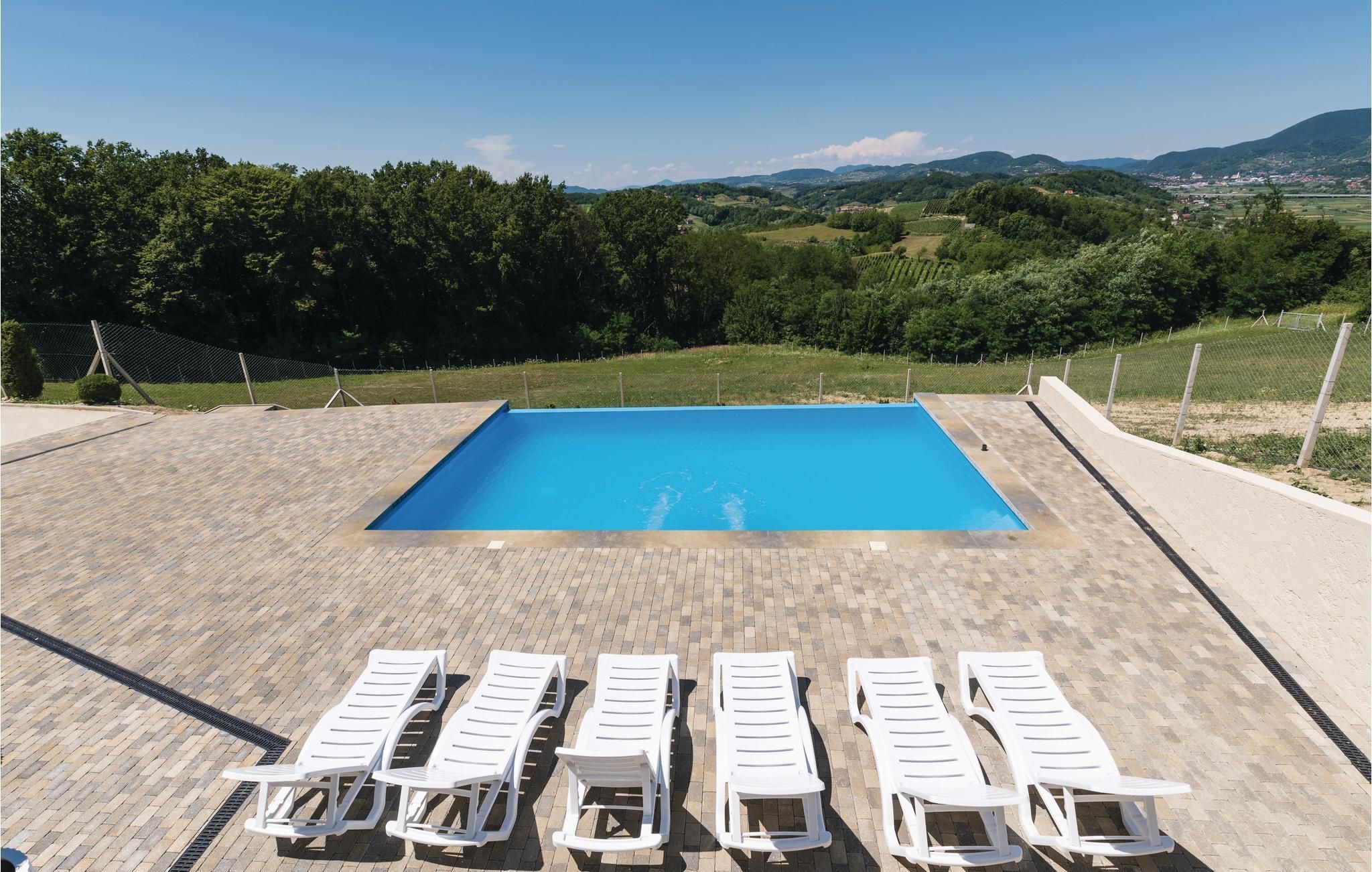 A rectangular swimming pool with a clear blue water surface, surrounded by a paved deck.