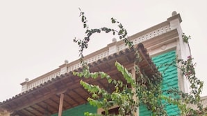 Un edificio a due piani con facciata verde, balconi in legno e un cartello che indica che si tratta di un hotel.