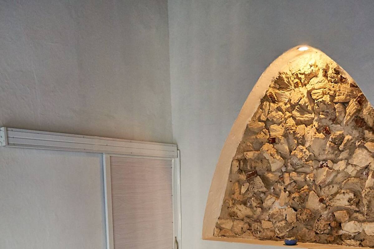 A bedroom with a bed, a wardrobe, and a stone wall feature.