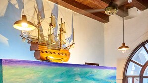 Una reception con un quadro a tema marittimo, un modellino di nave e un soffitto in legno.