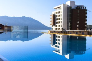 A modern hotel with a reflective pool, a mountain backdrop, and a clear sky. - Hotel Fagus by Aycon (Budva)