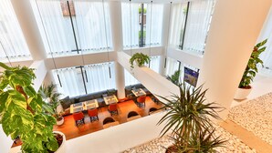 Un espace intérieur à plusieurs niveaux, aménagé avec des coins salon, des plantes en pot et un écran de télévision.