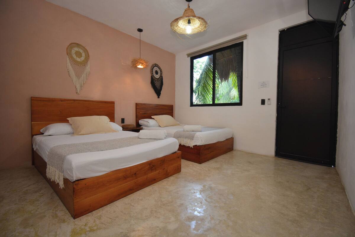 Un dormitorio con dos camas de madera, un ventanal grande y una puerta.
