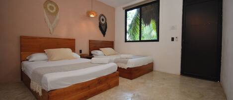 A bedroom with two wooden beds, a large window, and a door.