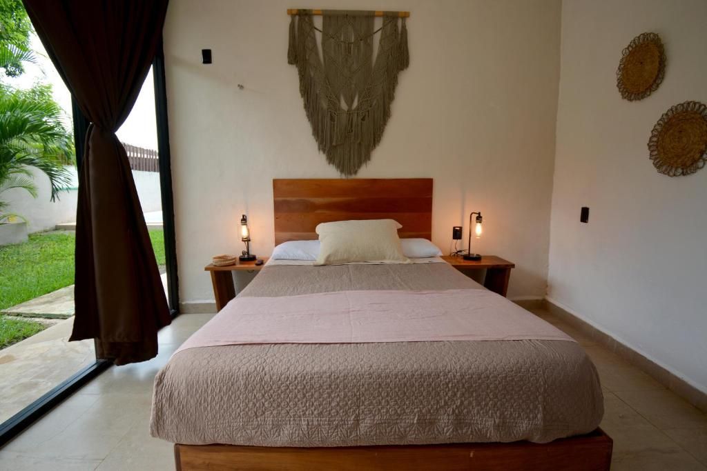 A bedroom with a large bed, two bedside tables, a headboard, and a view of the outdoors.