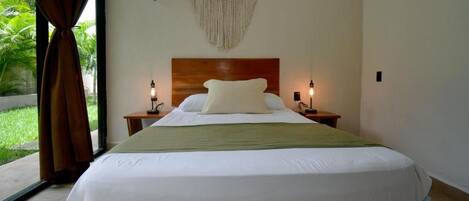 A hotel room with a large bed, two bedside tables, a wooden headboard, and a macrame wall hanging.