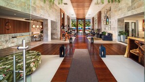 A spacious lobby with a wooden floor, seating areas, and a reception desk.