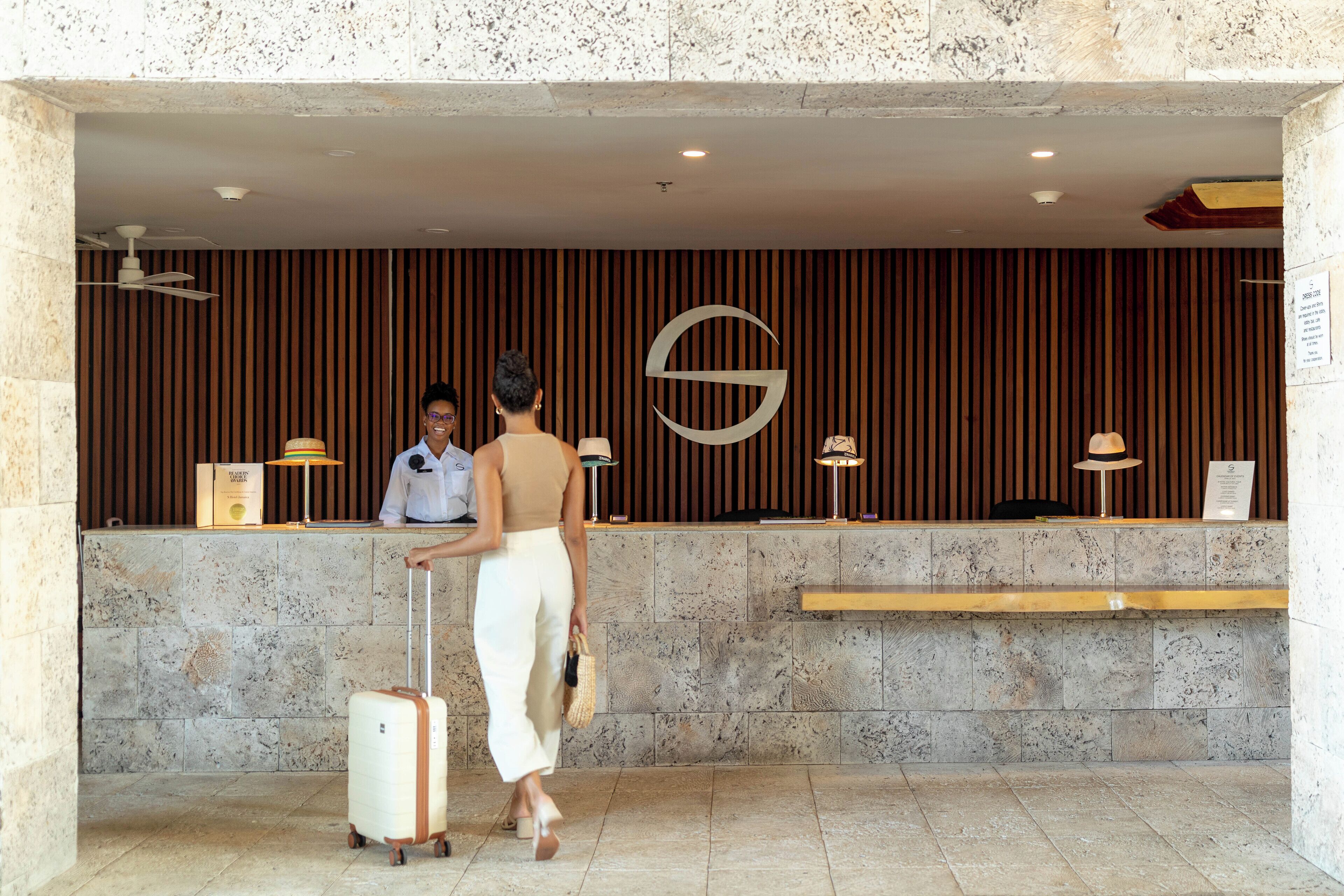 A reception area with a receptionist, a wooden panel wall, a large G logo, and a marble reception desk.