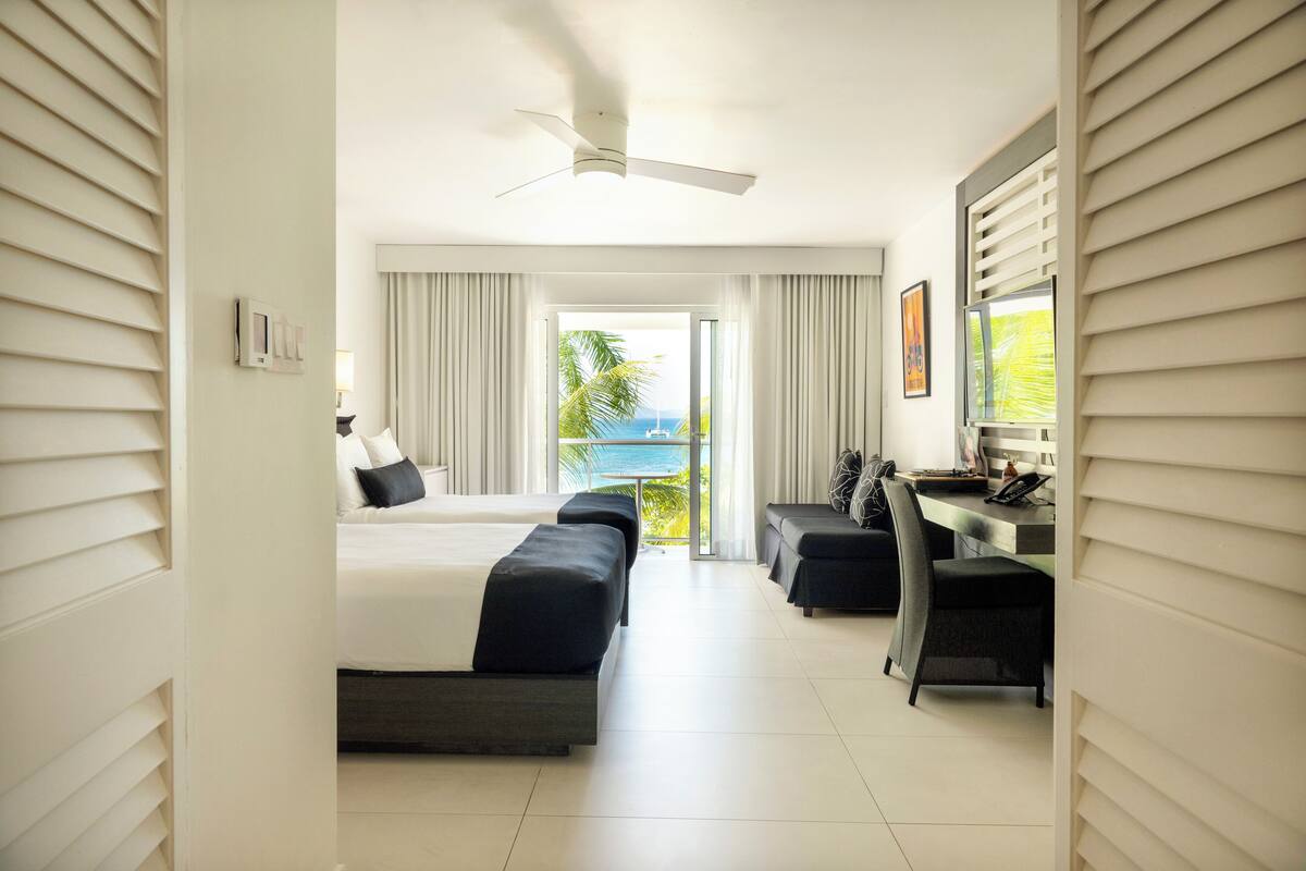 Una habitación de hotel con balcón, escritorio y cama.