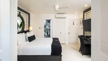 A bedroom with a bed, a desk, a chair, a ceiling fan, and a door.