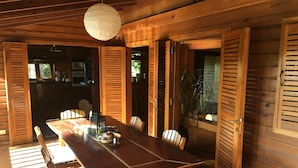 A wooden dining area with a table, chairs, and a hanging light fixture. - Villa Madera (Cabarete)
