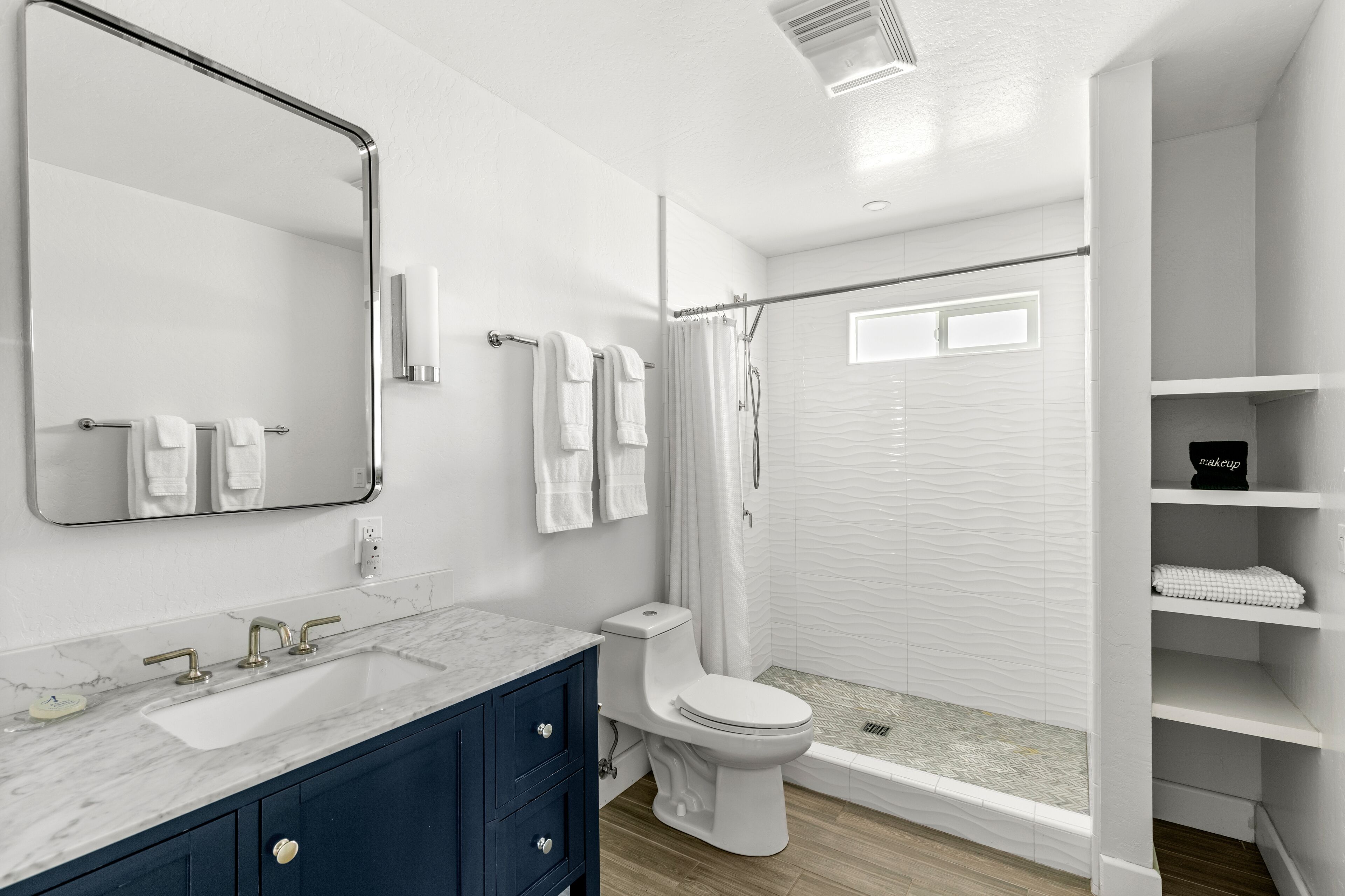 Un baño moderno con lavamanos, tocador y retrete blancos.
