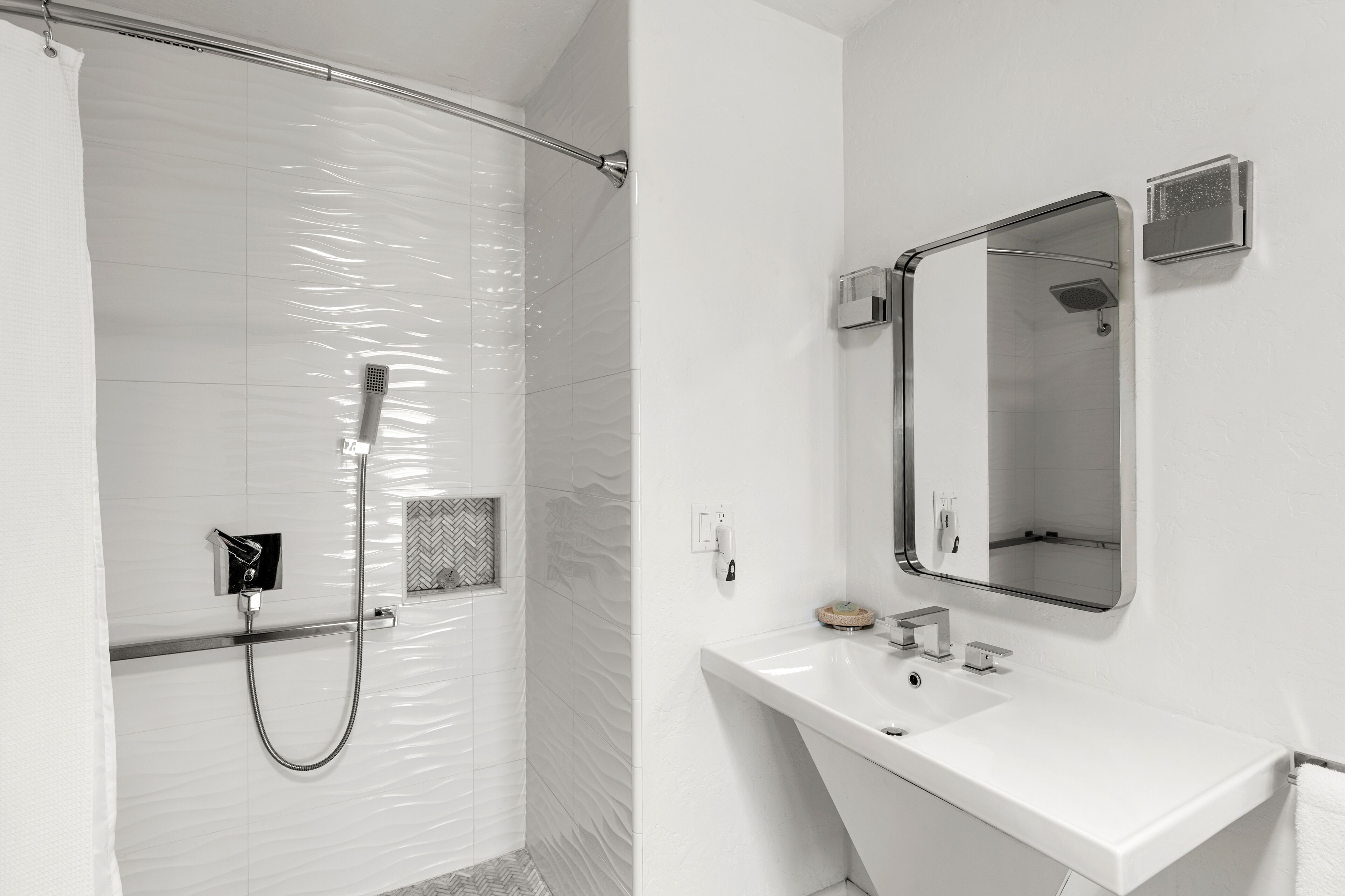 A modern bathroom with a shower, a sink, and a mirror.