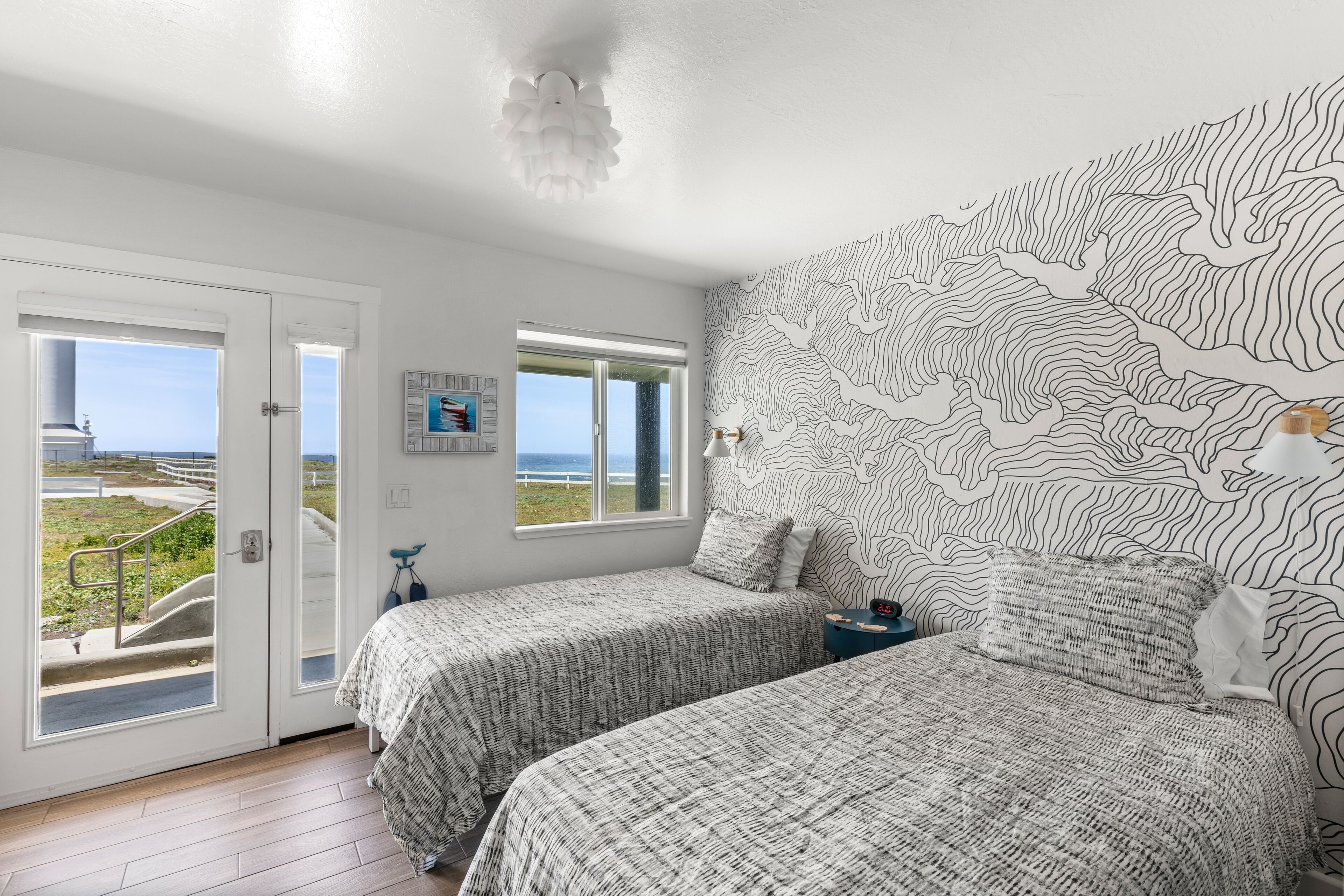 A bedroom with two beds, a large window, and a view of the outdoors.