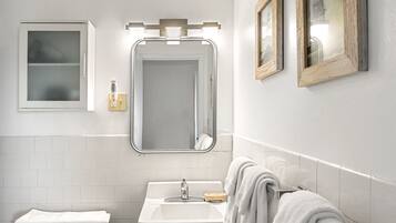 Un baño con un lavamanos blanco, un espejo y un inodoro.