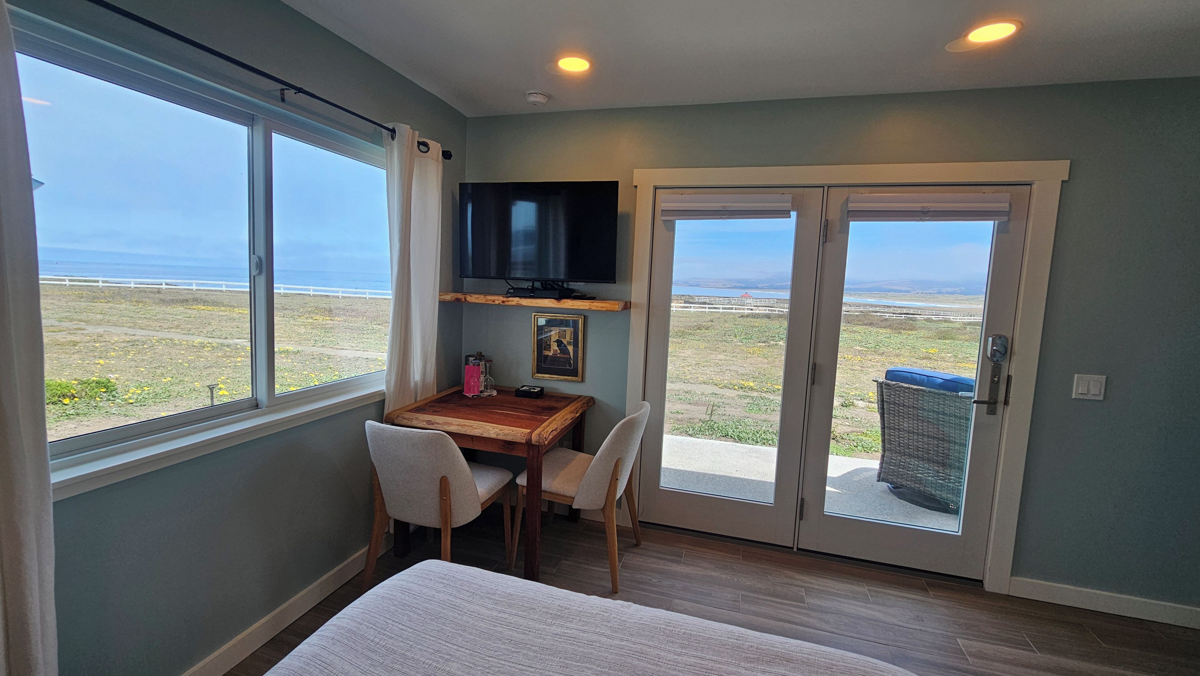 Una habitación con cama, escritorio, silla, televisor y vistas al exterior.