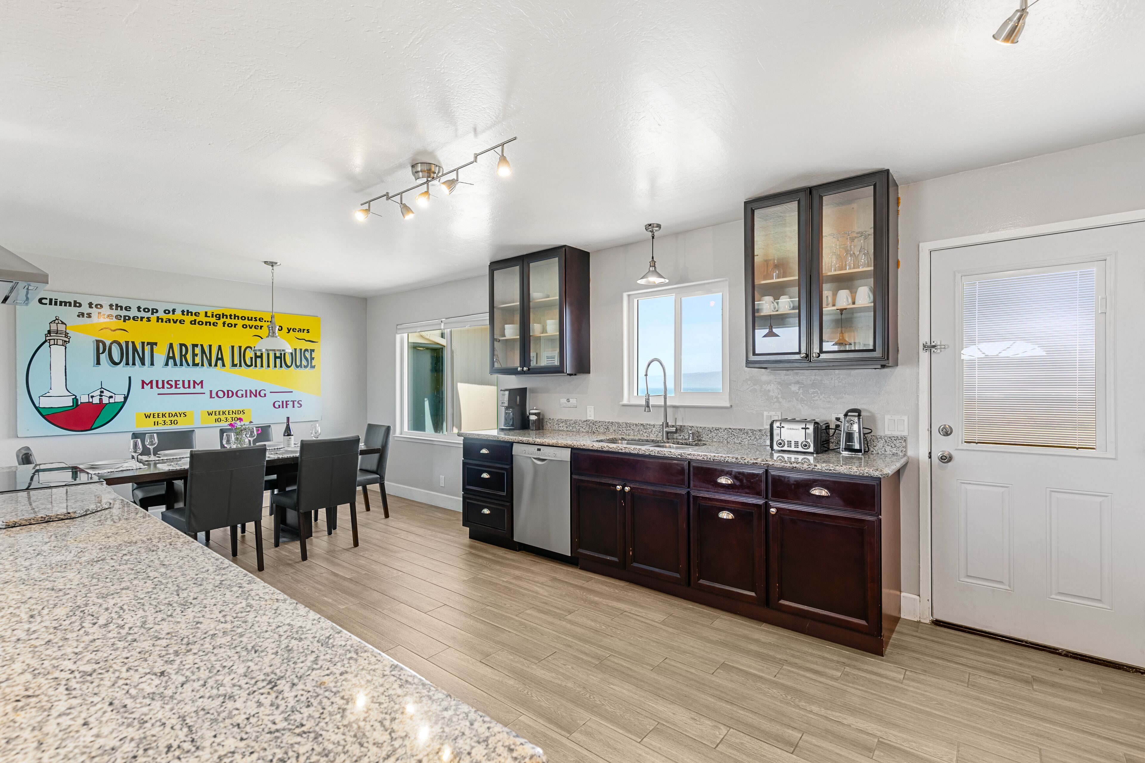 A modern kitchen with granite countertops, dark wooden cabinets, and a dining area with a table and chairs.