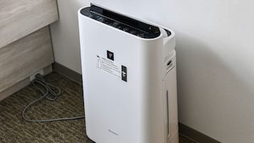 A white portable air conditioner with a control panel and a label on the side.