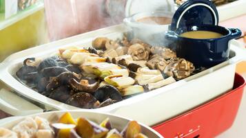 A buffet with various dishes including mushrooms, vegetables, and a pot of soup.