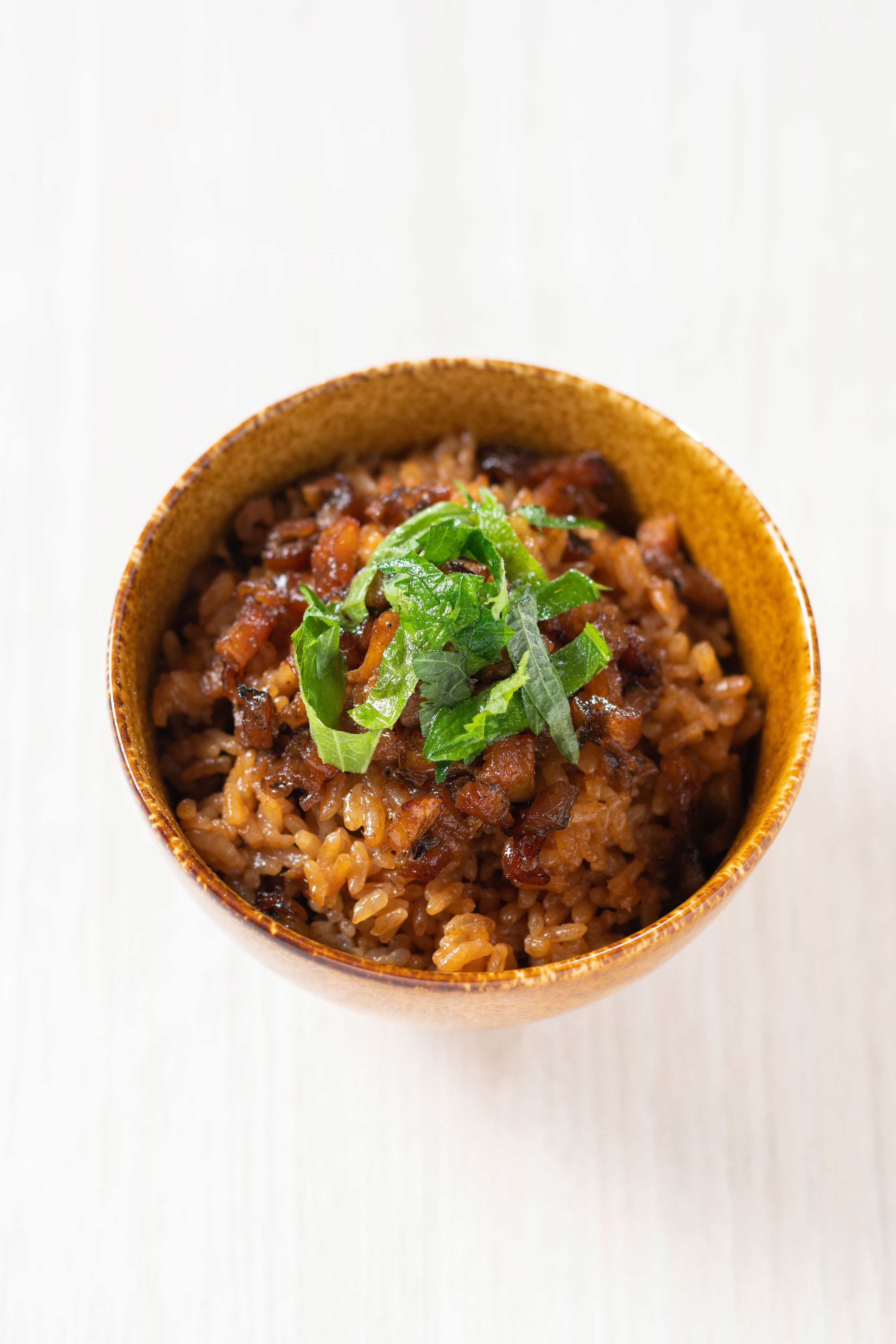 A bowl of rice with vegetables and herbs.