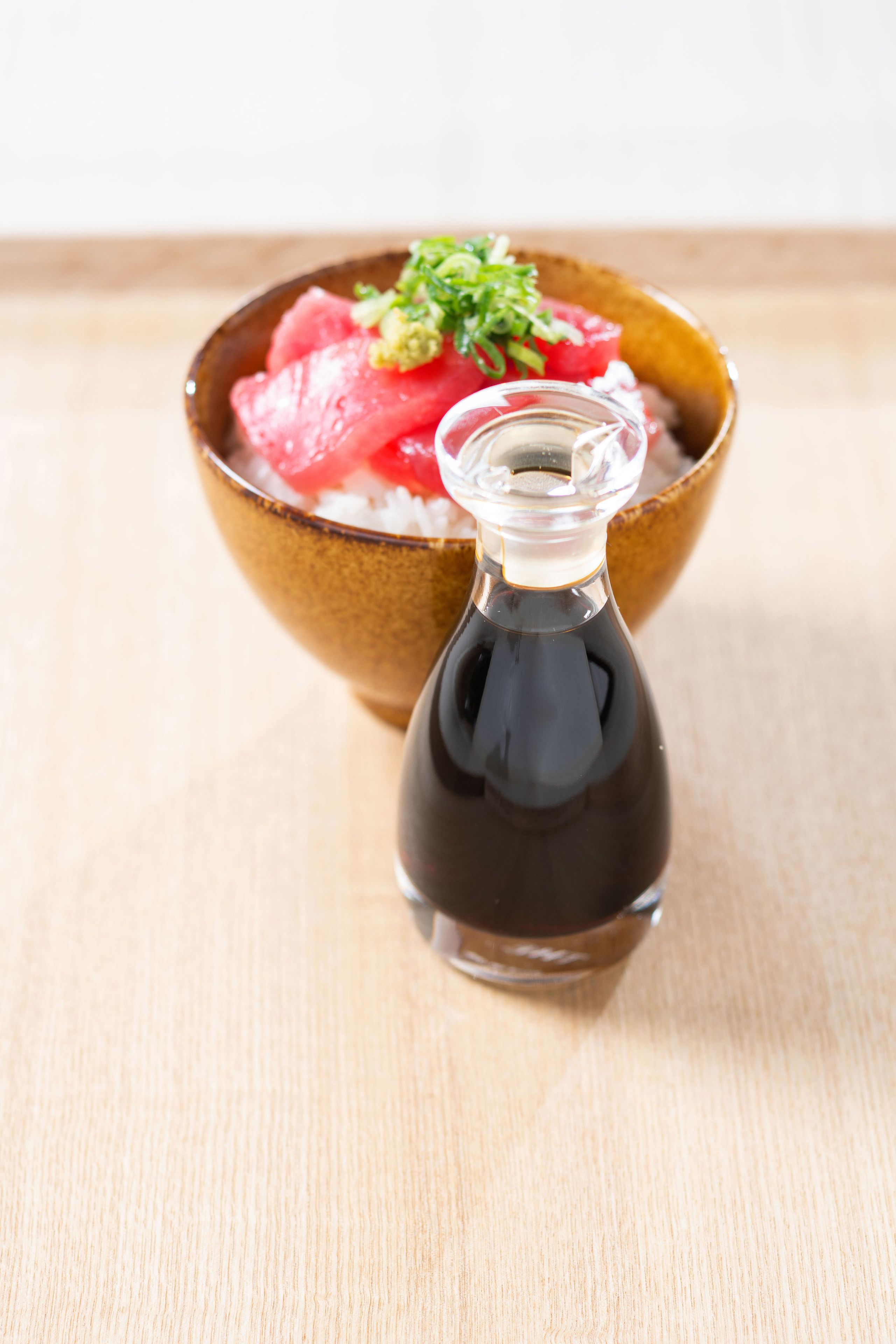 A bowl of food with a bottle of sauce.